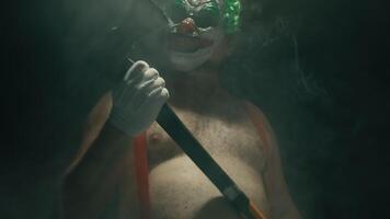 Man in a clown suit holding a knife and an axe video