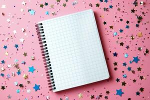 Blank notebook on pink background surrounded by colorful star confetti photo