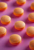 Bright orange circular candies arranged on a pink background photo