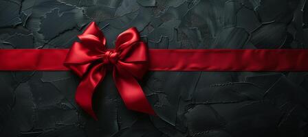 Red Satin Ribbon Bow on Black Textured Surface photo