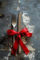 Cutlery with a red ribbon on a textured surface for a special occasion setting photo