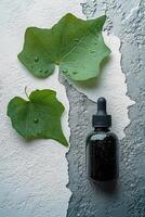 Botanical drops on textured surface with green leaves and liquid container photo