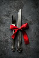 Cutlery with a red ribbon on a textured surface for a special occasion setting photo