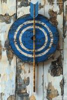 Arrow hitting blue and white target on weathered wooden surface photo
