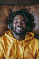 Man wearing headphones relaxes on a green couch with a smile indoors photo