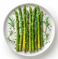 Four Green Asparagus Spears With Salt and Herbs on a Grey Plate photo