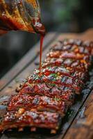Delicious barbecue ribs being glazed with sauce on a wooden cutting board photo