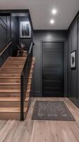 Stylish hallway with black walls, modern staircase, and natural accents near front door photo