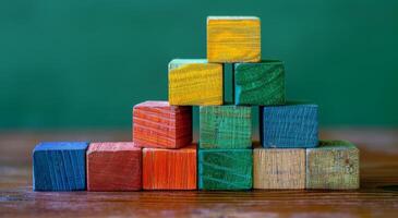 Colorful Wooden Blocks Stacked in a Pyramid Shape on a Wooden Table Against a Green Background photo