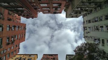 Looking up at a vibrant urban alleyway surrounded by historic buildings and cloudy sky photo