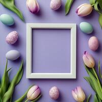 Colorful Easter eggs arranged with flowers around a blank picture frame on a purple background photo
