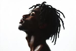 Profile of a young man with dreadlocks gazing upwards against a soft background photo
