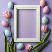 Colorful Easter eggs arranged with flowers around a blank picture frame on a purple background photo