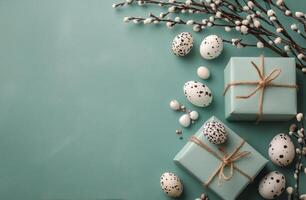 Decorative Easter gifts with speckled eggs and willow twigs on a teal background photo
