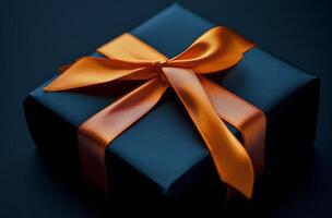 Elegant black gift box with orange ribbon on textured dark surface photo
