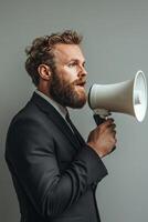 A man with a beard and gray hair passionately addresses an audience using a megaphone photo