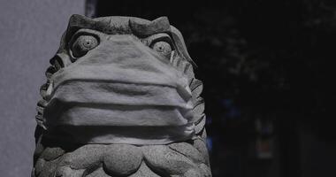 A statue of Guardian dog wearing mask at Meguro fudo temple in Tokyo copyspace video