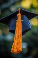 Graduating cap with golden tassel displayed outdoors against a blurred background photo