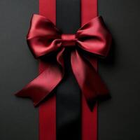 Elegant red ribbon with a bow displayed on a textured black background for gift wrapping photo
