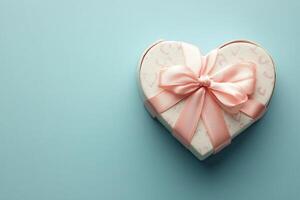 Heart shaped gift box with pink ribbon on a light blue background adorned with elegant touches photo