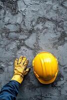Construction worker placing yellow hard hat on textured gray wall in building site area photo