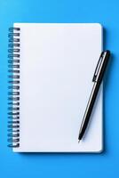 A brown notebook and a black pen resting on a teal table surface during daytime photo