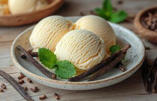 Creamy vanilla ice cream scoops with mint leaves and vanilla pods on a white plate photo