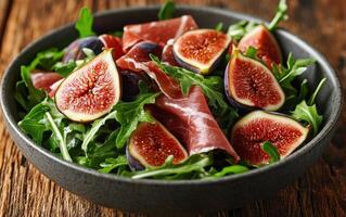 Fresh arugula salad topped with figs and prosciutto served in a rustic bowl photo
