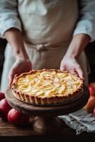 A baker presents a freshly made apple pie on a wooden pedestal surrounded by fresh apples photo