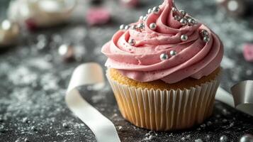 Delightful pink frosted cupcake with edible pearls on a marble surface ready for celebration photo