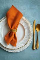 A beautifully set autumn themed dining table with orange leaves and elegant tableware photo