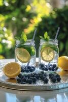 Refreshing blueberry lemonade served in mason jars with fresh mint outside on a sunny day photo