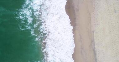 waves arriving at the shore of a beach aerial zenithal drone view, background texture for beach summer concept video