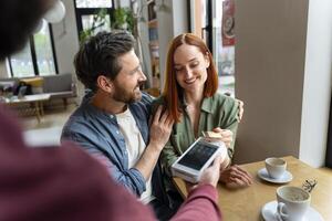 Happy couple making a card payment in a cafe photo