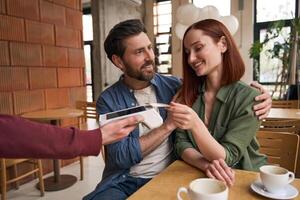 Couple paying restaurant bill using nfc technology on mobile pos terminal photo