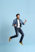 Excited young man jumping and celebrating with fists in the air photo