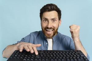 Excited man celebrating success working from home office using computer keyboard photo