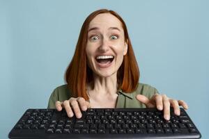 Excited woman using computer keyboard on blue background photo