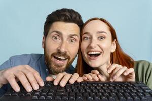 Young couple using computer is amazed by what they see on the screen photo