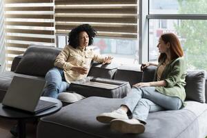 Two female colleagues relaxing and talking during break time in the office photo