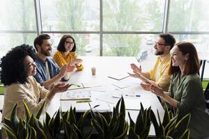 Diverse business team clapping after successful brainstorming meeting photo