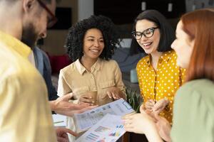 Happy diverse business team discussing financial report with charts and graphs photo