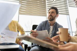 Creative business team brainstorming during meeting discussing documents photo