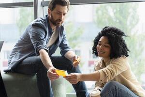Coworkers exchanging ideas using sticky notes during brainstorming session photo