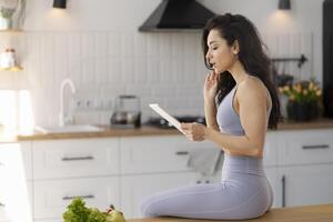 Fit woman reading shocking news on tablet in kitchen photo