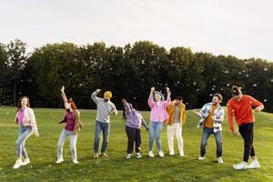 Group of friends dancing and having fun with soap bubbles in the park photo