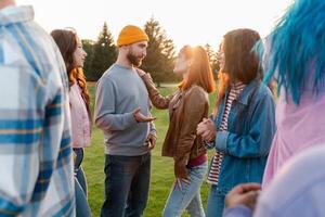 Group of friends having conversation outdoors at sunset time photo