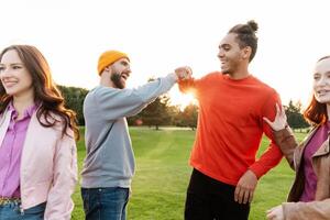 Group of friends having fun and fist bumping in the park photo