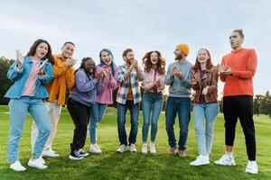 Group of diverse young people applauding and cheering outdoors photo