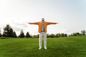 Young man enjoying freedom standing on grass field with open arms photo
